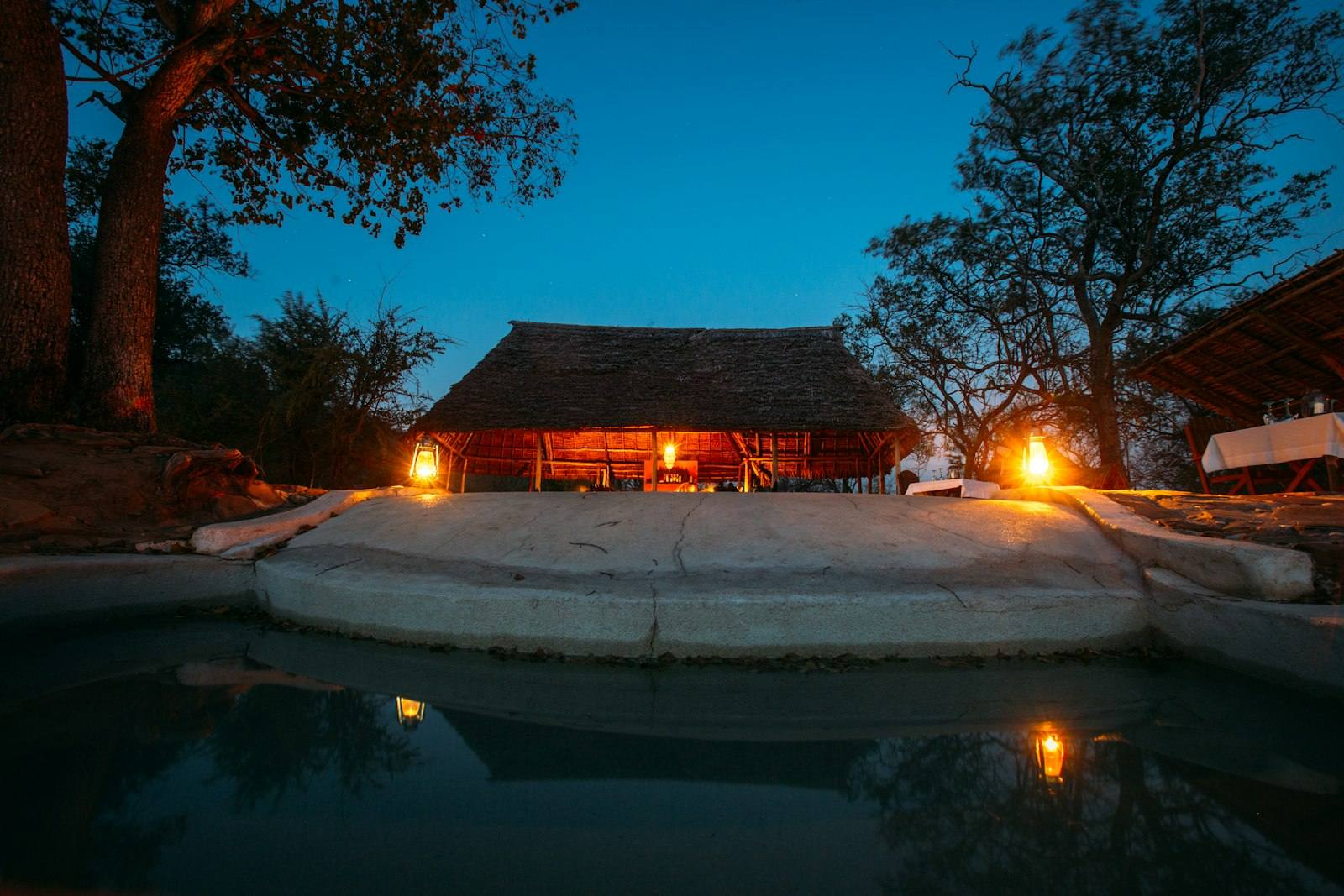 Lodge de safari iluminado junto a la alberca al anochecer